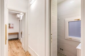 A hallway with a wooden floor, white walls, and a tiled shower area. - Quiet Elegance Retreat Apartment Trastevere Family-friendly (Roma)