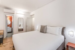 Ein modernes Schlafzimmer mit einem großen Bett, einem Nachttisch, einem Spiegel und einer Tür zu einem Badezimmer.