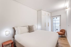 Ein Schlafzimmer mit einem Bett, einem Nachttisch, einem Kleiderschrank und einem Sessel.