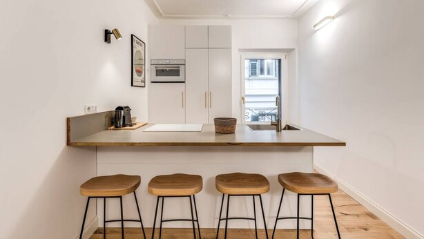 A compact kitchen with a central island, four stools, a microwave, and a window. - Quiet Elegance Retreat Apartment Trastevere Family-friendly (Roma)