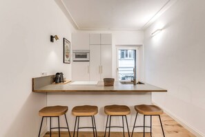 A compact kitchen with a central island, four stools, a microwave, and a window. - Quiet Elegance Retreat Apartment Trastevere Family-friendly (Roma)