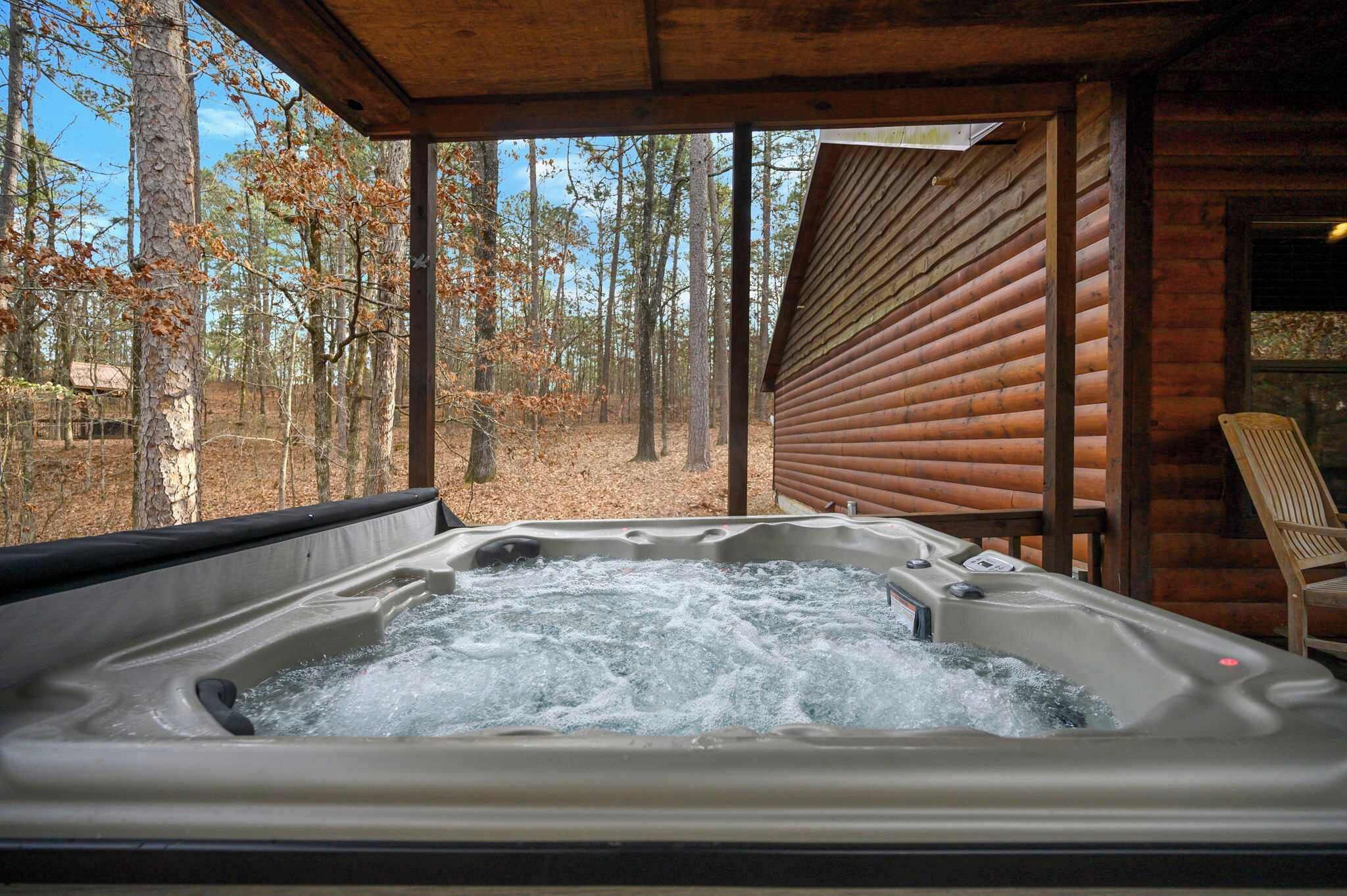 A hot tub in a wooden cabin with a forest view.