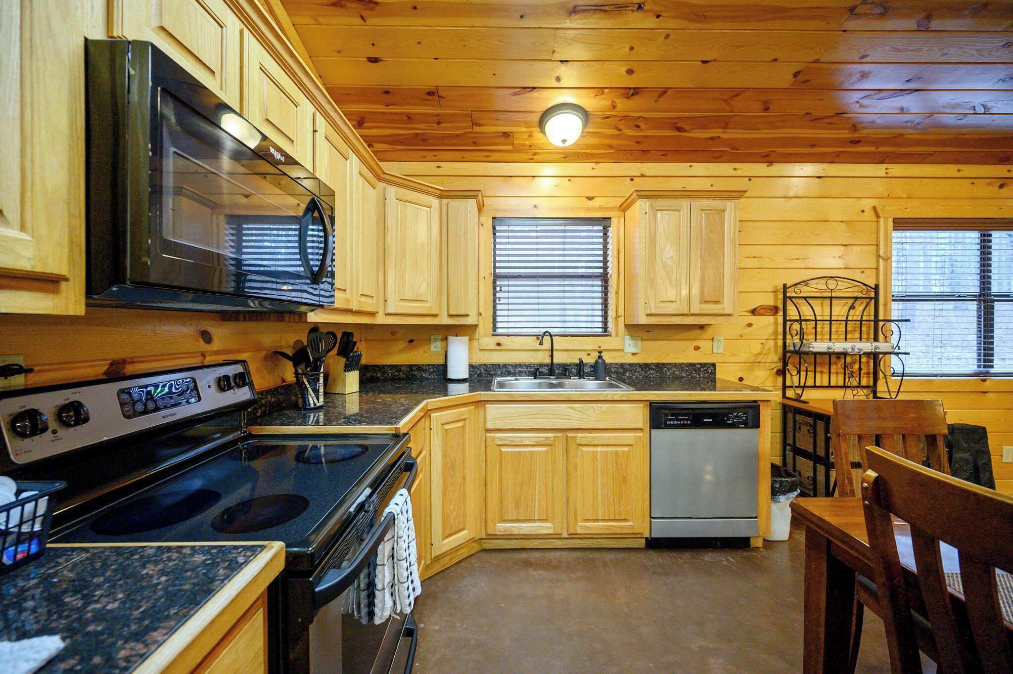 Una cocina con armarios de madera, microondas, estufa, fregadero y lavavajillas.