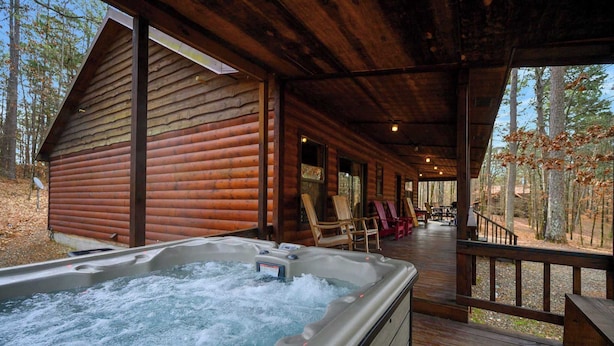 Uma cabana de madeira com hidromassagem e área de estar externa.