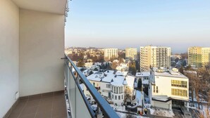 A balcony with a view of a cityscape, including several high-rise buildings and a snow-covered ground. - Sunny Studio with Sea View | Balcony (Gdynia)