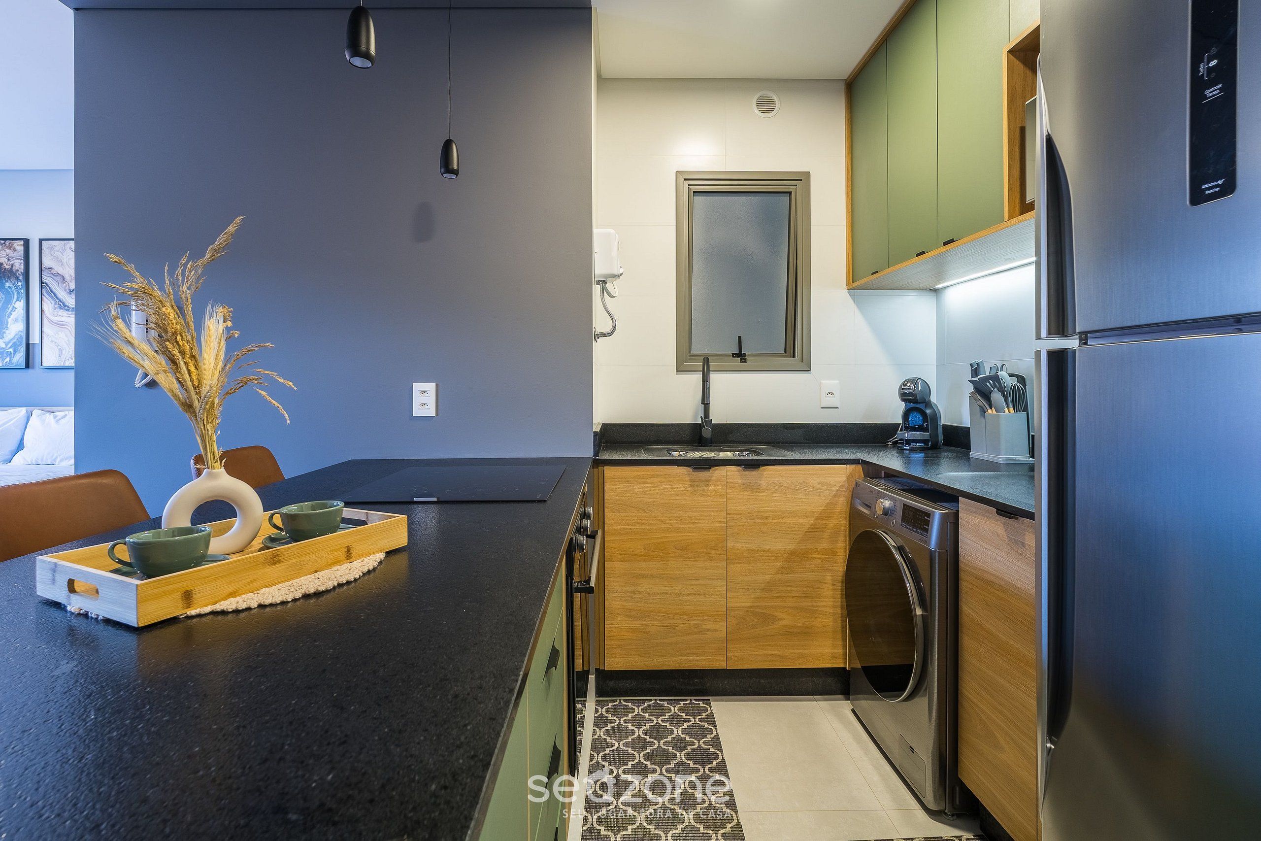 A modern kitchen with a built-in washer and dryer, wooden cabinets, and a black countertop.