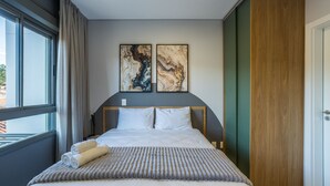 A hotel room with a bed, two paintings on the wall, a window with curtains, and a door. - Stay in Comfort and Convenience Near Ufsc - Ters (Florianópolis)
