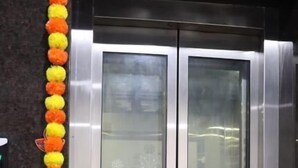 Een lift met metalen deuren en een groene vloer.