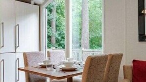 A dining area with a table set for four, surrounded by upholstered chairs. - Deers Leap - Kelling Heath Holiday Park - 22250 (Holt)