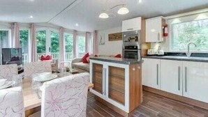 A modern kitchen with white cabinets, a built-in oven, and a window overlooking greenery. - Deers Leap - Kelling Heath Holiday Park - 22250 (Holt)