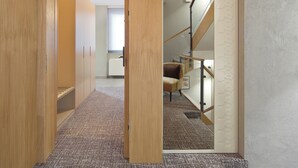 A hallway with wooden doors, carpeted flooring, and a staircase leading to another room.
