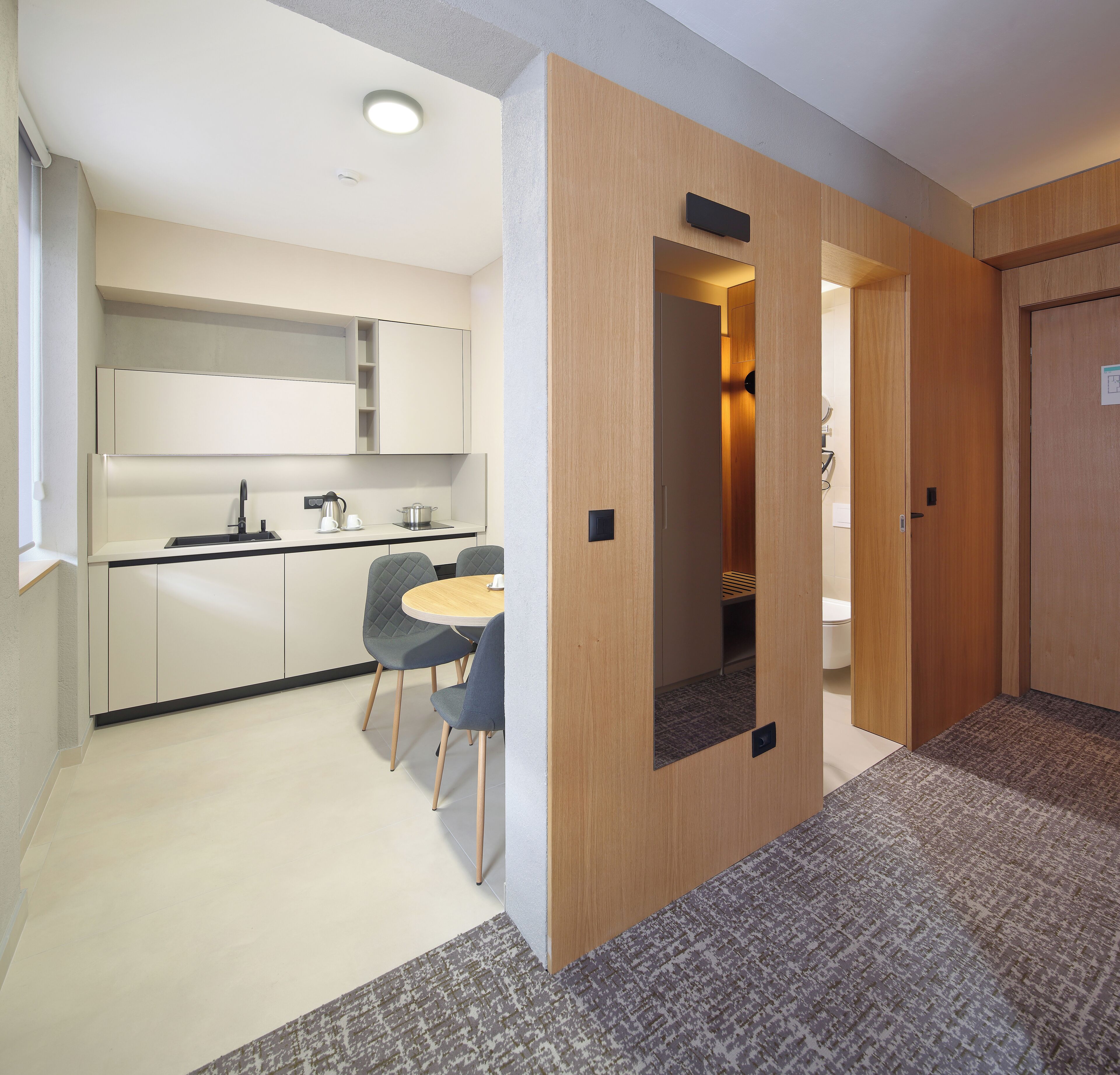 A modern kitchen with a dining area, wooden walls, and a carpeted floor.