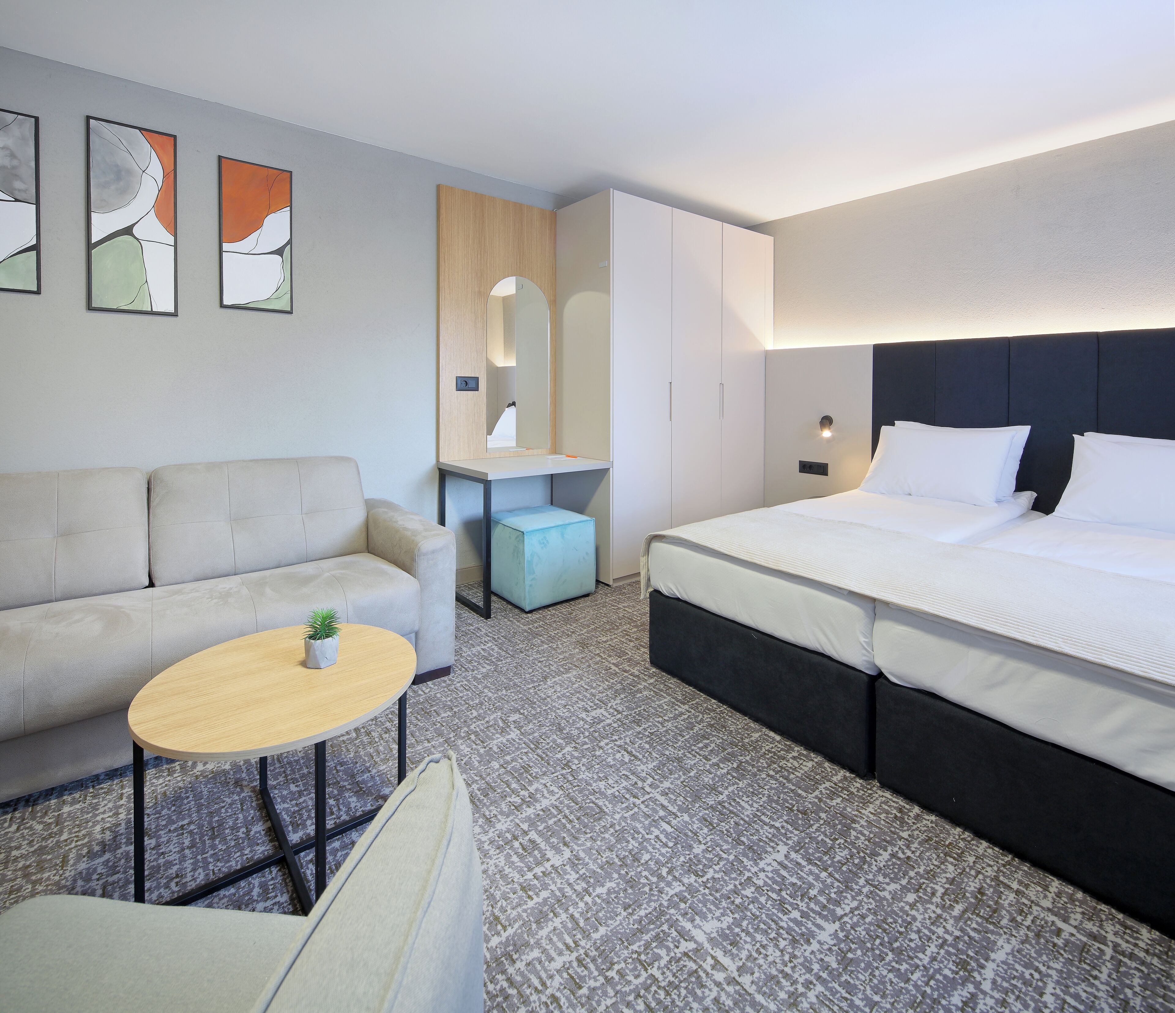Ein modernes Hotelzimmer mit Bett, Sofa, Schreibtisch und einem kleinen Tisch.