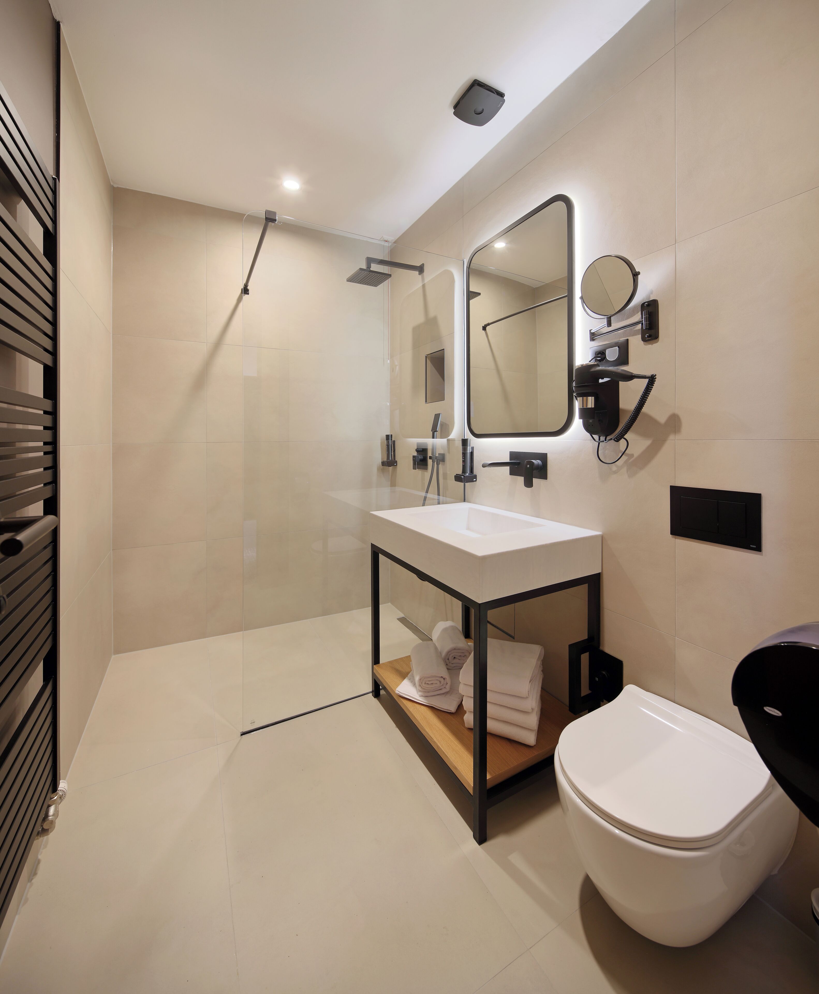 Un baño moderno con cabina de ducha de vidrio, inodoro blanco y tocador con espejo.