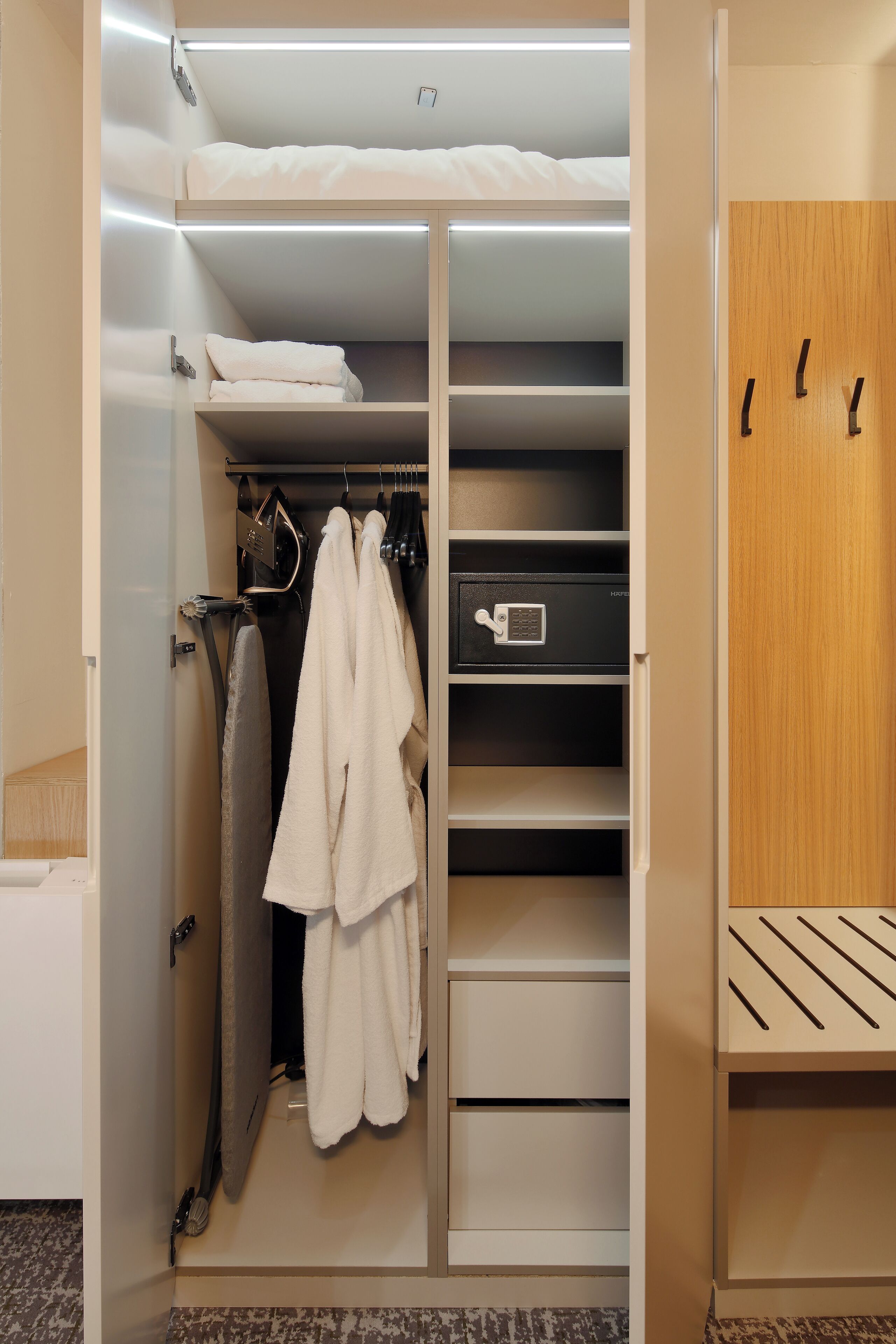 Ein begehbarer Kleiderschrank mit Kleiderhaken, Regalen und einer Aufbewahrungsbox.