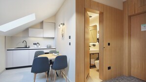 A modern kitchen with a dining area, a visible bathroom, and a wooden door.
