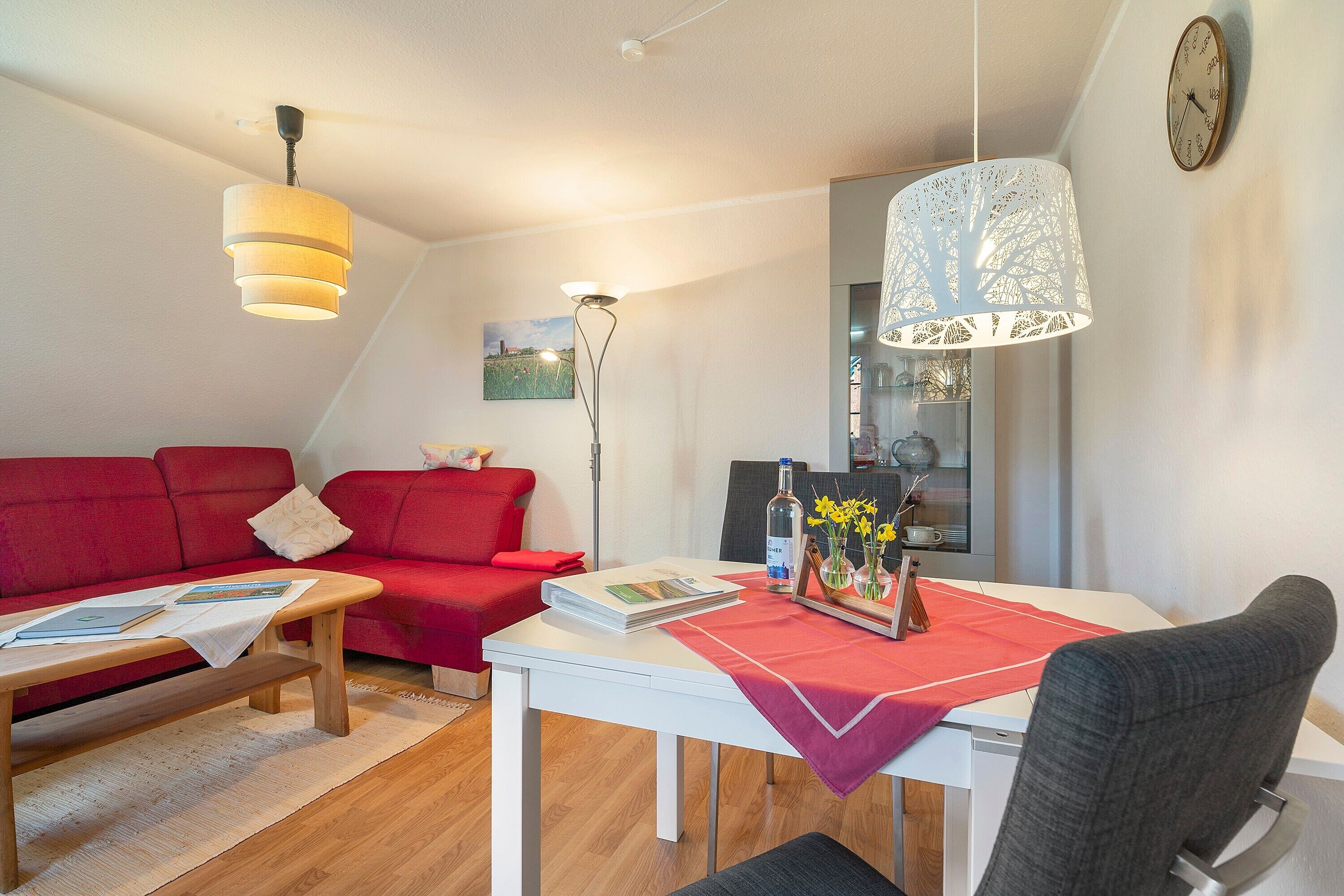 A living room with a red sofa, a white table, and a grey chair.