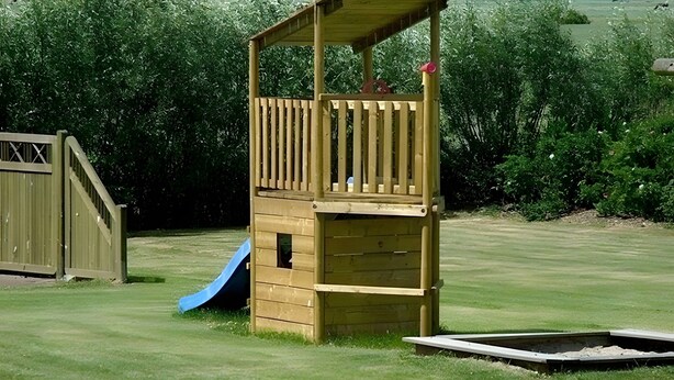 Une structure de jeu en bois, dotée d’un toboggan et d’une petite plateforme.