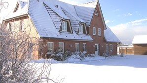 Een groot, bakstenen huis met een steile kap en dakramen.