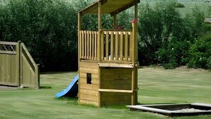 Een houten speelconstructie met een glijbaan en een klein platform.