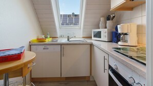 Eine Küche mit Fenster, Spüle, Mikrowelle und Herd.