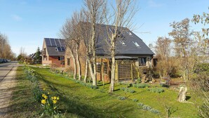 Ein Haus mit Solaranlage, ein Garten mit Narzissen und ein Holzzaun.