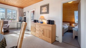 Ein Zimmer mit Holzboden, einem Bett, einem Schreibtisch mit Lampe, einem Stuhl und einem Fenster.