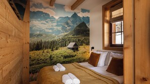 A bedroom with a mountain landscape mural, a wooden bed frame, and a window with a view of the outdoors. - Karpielówka Suites Parking & Mountain View by Downtown Apartments (Kościelisko)