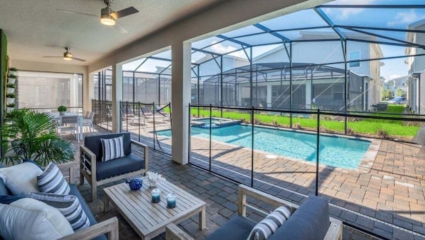 A covered outdoor area with a pool, seating, and a view of a house. - 9 Bedroom With Everything For Happiness! 9 Home (Kissimmee)