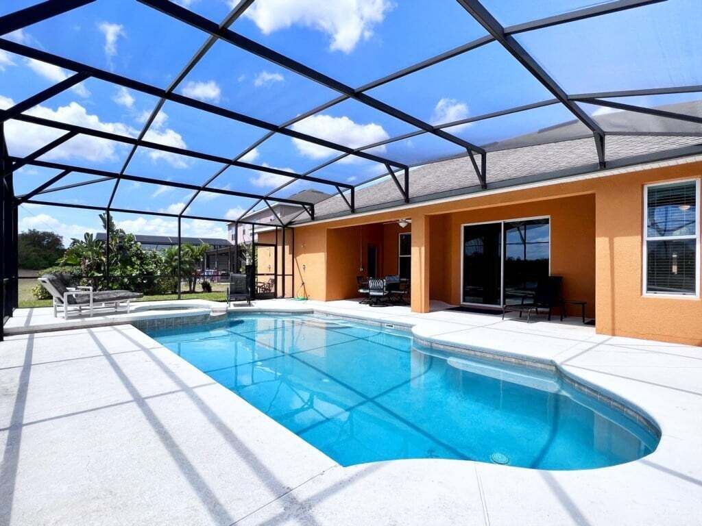 Una piscina con recinto in vetro, circondata da una terrazza con arredi da esterno.