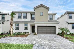 A modern two-story house with a garage, a driveway, and a well-maintained lawn. - Super Fun Home For Kids & Families - Private Pool 12 Bedroom Villa (Kissimmee)