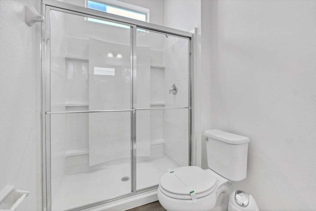 Une salle de bain avec une douche à parois de verre, des toilettes blanches et un lavabo blanc.