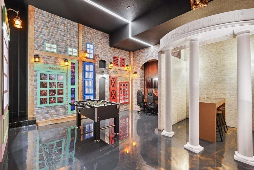 Un hall d’entrée avec une table de baby-foot, un espace bar et un coin salon agrémenté d’une colonne blanche.