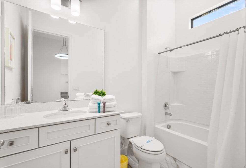 Een moderne badkamer met een witte wastafel, spiegel en toilet.