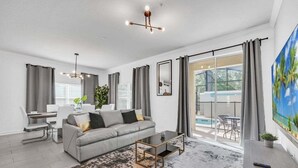 Een moderne woonkamer met een grijze bank, een salontafel en een groot raam met grijze gordijnen.