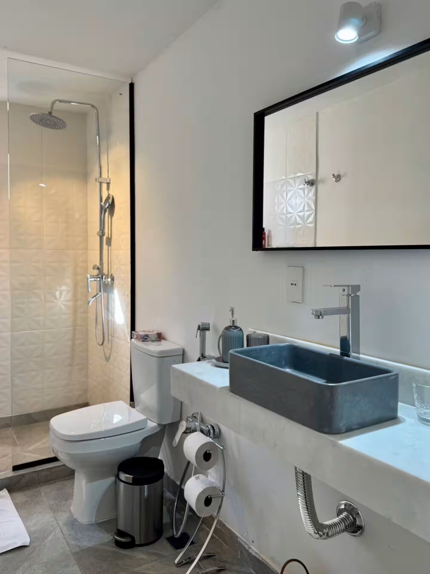 A modern bathroom with a shower, toilet, sink, and a mirror above the sink.