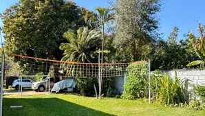 Un patio trasero con césped, valla de madera y diversas plantas y árboles.