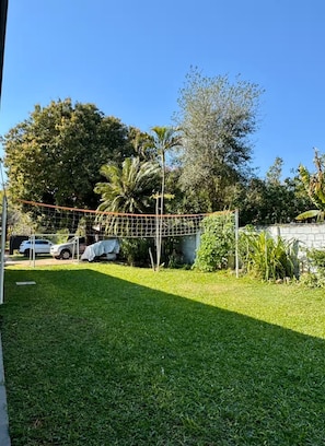 Un patio trasero con césped, valla de madera y diversas plantas y árboles.