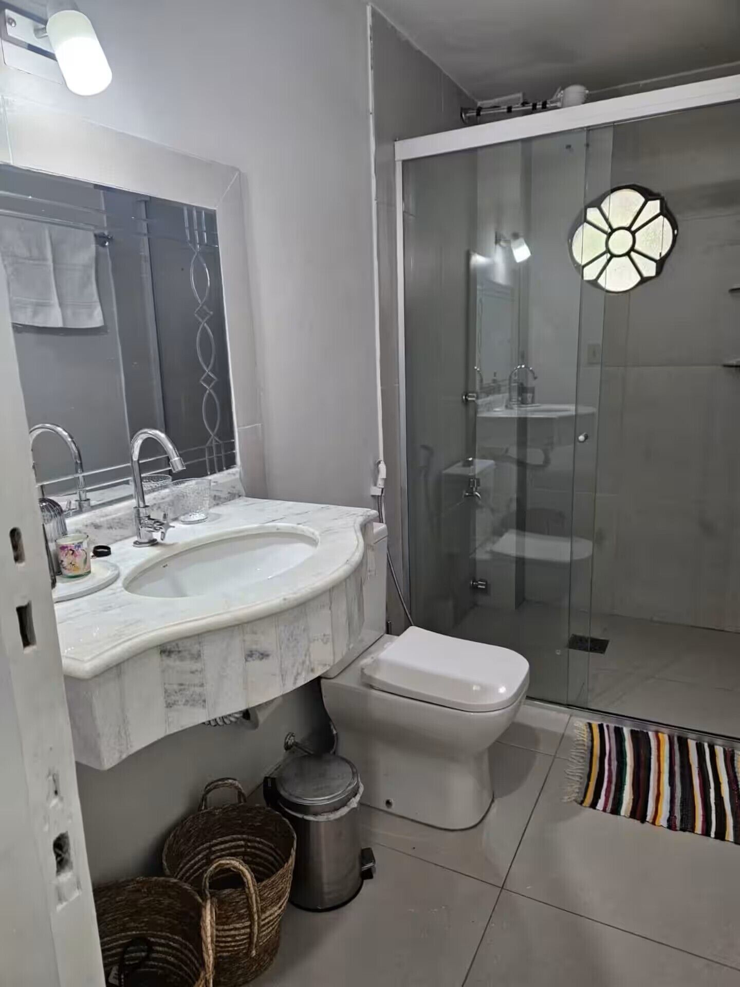 Ein modernes Badezimmer mit Marmorwaschtisch, Toilette und einer Duschkabine.