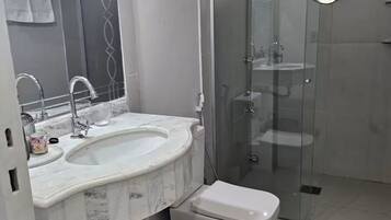 Ein modernes Badezimmer mit Marmorwaschtisch, Toilette und einer Duschkabine.
