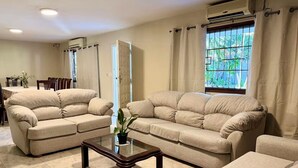 Una sala de estar con sofás color beige, una mesa de centro de cristal y un comedor con mesa y sillas.