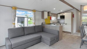 Una cocina moderna con microondas, estufa y armarios. Hay un sofá gris y una mesa de comedor con sillas.