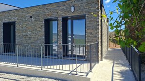 A modern building with stone facade, large windows, and a metal railing. - The Douro Nest — Casa com Piscina Privada perto de Pinhão (Valença do douro)