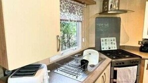 A compact kitchenette with a stove, toaster, and sink. - Nutty Nanny's - Kelling Heath Holiday Park - 22251 (Holt)