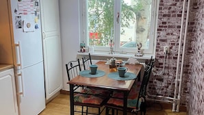 Een kleine keuken met een houten eettafel, stoelen en een koelkast.