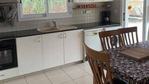 A modern kitchen with white cabinets, a black countertop, and a dining area with a table and chairs.