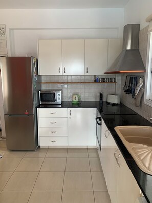 A kitchen with white cabinets, a stainless steel refrigerator, a microwave, a kettle, and a sink. - Villa Eldora Lysos With Beautiful pool (Lysos)