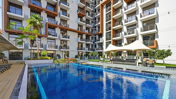 Un moderno edificio de apartamentos con piscina, zona de estar al aire libre y un jardín bien cuidado.