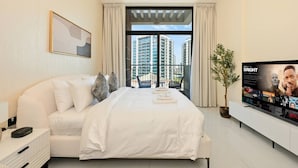 Una habitación de hotel moderna con una cama grande, un televisor y un balcón con vistas a la ciudad.