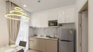 Una cucina moderna con mobili bianchi, forno a microonde integrato e frigorifero in acciaio inossidabile.